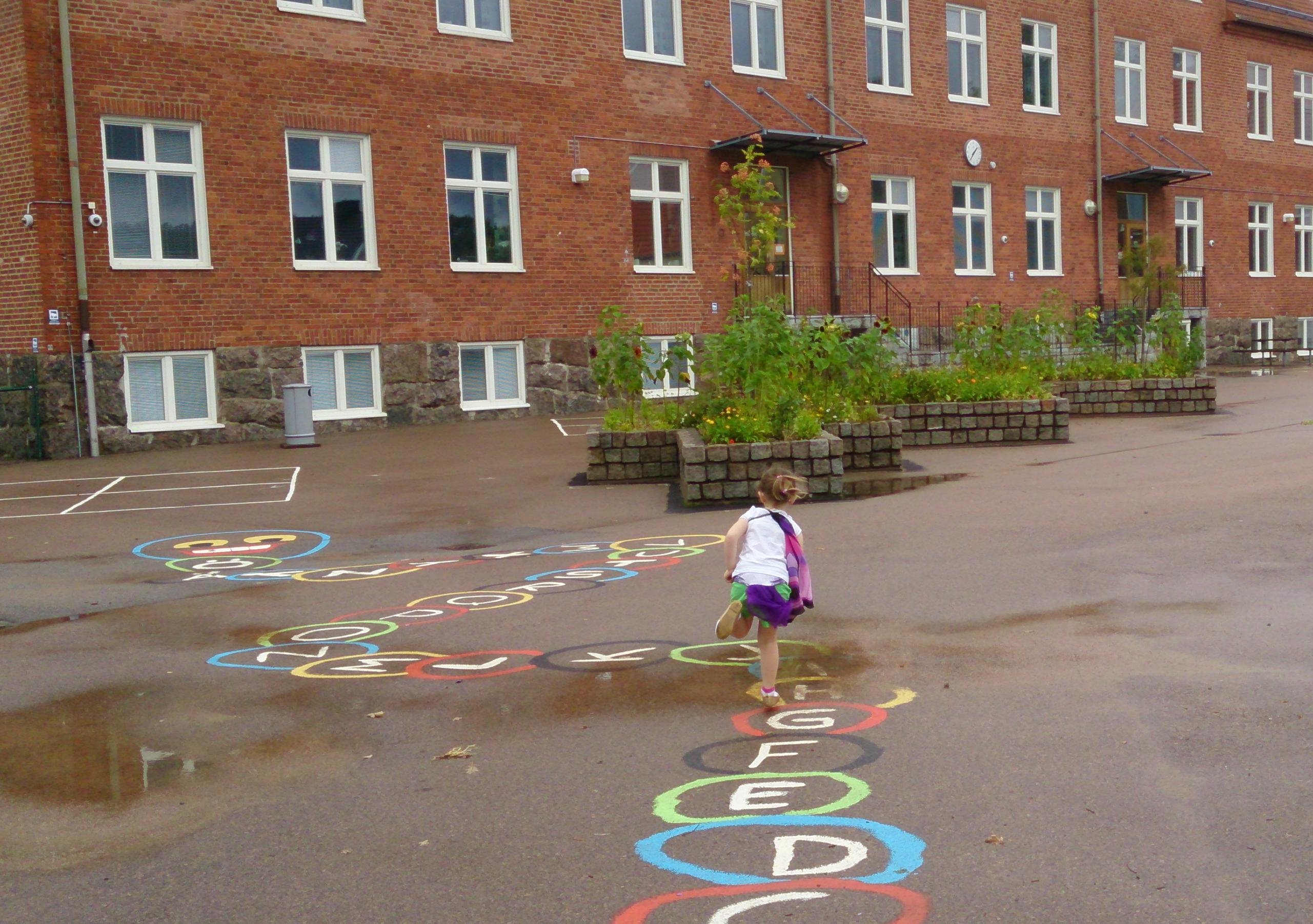 Bilden visar en flicka som hoppar runt på en skolgård