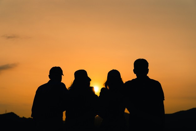 Fyra personer tittar på en solnedgång.