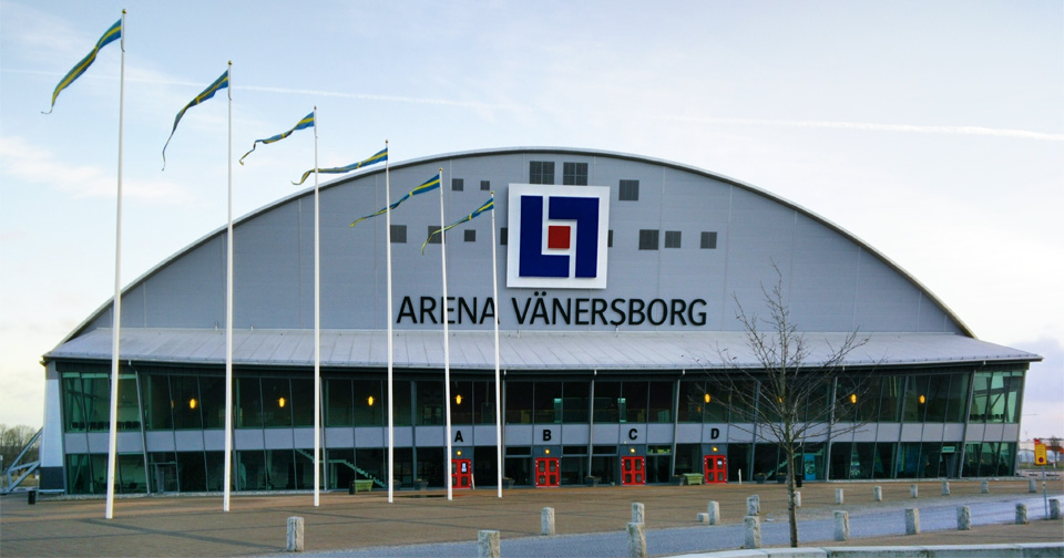 Vy över framsidan av Arena Vänersborg med flaggstänger i förgrunden.