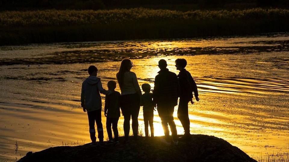 En familj vid havet i solnedgång