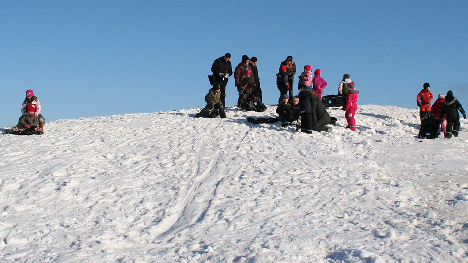 Barn som åker pulka på en snöklädd kulle.