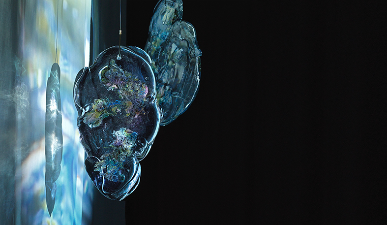 Hängande glasplattor i blånyanser i ett mörkt rum