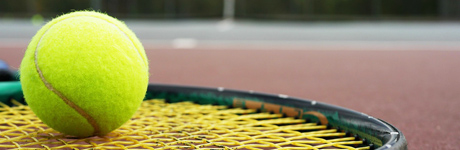 En tennisboll vilar på ett tennisrack