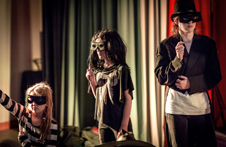 Tre unga teaterelever spelar teater med masker för ögonen.