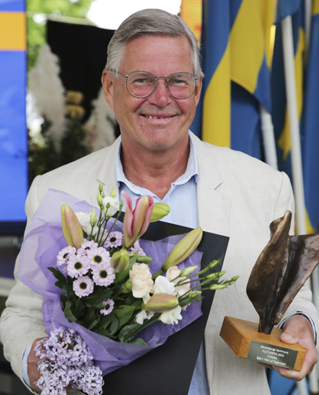 En glad Björn visar upp sin prisstaty i brons och blommor.