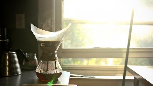 Kaffebryggare på diskbänk mot ett öppet fönster