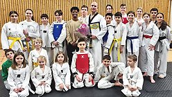 Roger Milde står med diplom och blommor bland barn och ungdomar efter ett träningspass av Taekwondo.