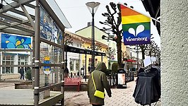 Vy över gågatan med en regnbågsfärgad fasadflagga i förgrunden.