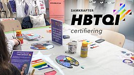 Bord med penslar och färger på Timjan. Ovanpå ligger logotypen med texten Hbtqi-certifiering.