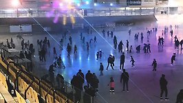 Vy över isen på Arena Vänerborg. Många skridskoåkare och färgglada lampor.